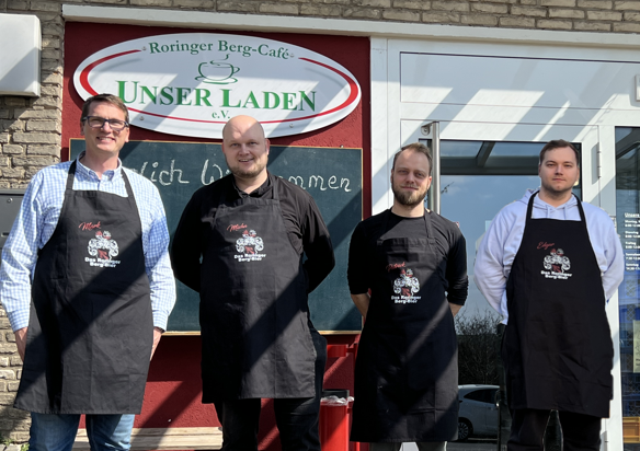 Vier Brauer in Schürzen mit Bier-Logo vor dem Roringer Berg-Café Unser Laden