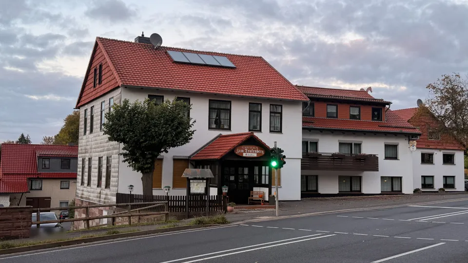 Gasthaus Zum Drakenberg von der B 27 aus: weißes Haus mit roten Ziegeldächern, Windfang mit dem Schild Gasthaus Zum Drakenberg, rechts der Hotelflügel mit Balkon