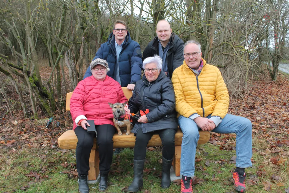 Fünf Personen und ein Hund auf der neuen Holzbank am Feldrand